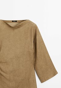 Robe en tissu marron doux avec un large col, des manches trois-quarts et des détails subtils de coutures diagonales. Texture lisse, sans motifs apparents.