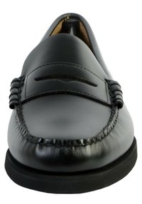 Mocassins en cuir noir avec un bout arrondi, des coutures décoratives et de simples accents horizontaux sur le dessus. La semelle en caoutchouc est légèrement surélevée.