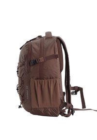 Brown nylon backpack with adjustable straps, mesh back panel, side pockets, and cord loops for extra storage. Features a compact, structured shape.