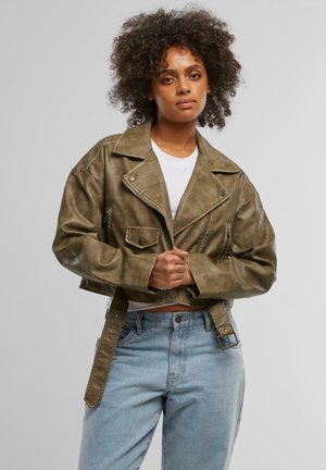 Kuttet khaki kunstlærjakke med brede revers, glidelåslommer og belte i midjen; parret med lyseblå høytlivsjeans.