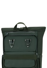 Zöld hátizsák felső fedéllel, cipzáros zárással és két f�émklipszel. Simább szövettextúrával és strapabíró kézi fogantyúval rendelkezik a hordozáshoz.