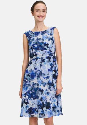 Bloemenjurk in blauwe tinten met een mouwloos ontwerp, wikkel taille-detail en vloeiende stof. Bevat een mix van abstracte bloemenpatronen.