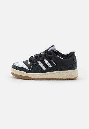 Lage Adidas sneaker in zwart, wit en donker groen met zwarte veters, drie witte strepen en een beige zool op een witte achtergrond.