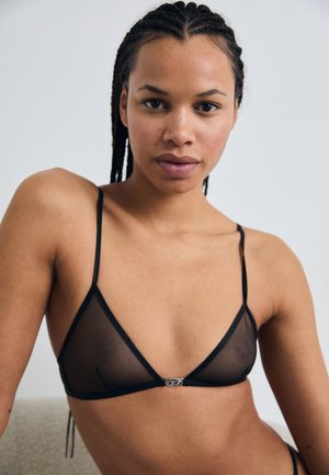 Zwarte mesh driehoekige bralette met dunne bandjes, voorzien van een klein zilveren hardwaredetail in het midden. Minimalistisch ontwerp en doorschijnende textuur.