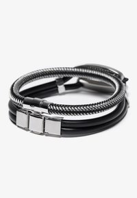 Sort læder- og flettet metalarmbånd med en sølvfarvet lås og rektangulære metaldetaljer, med et lagdelt design.