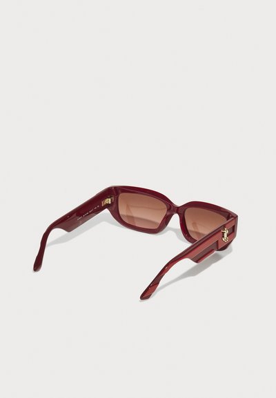 Red oversized sunglasses with a glossy finish, rectangular shape, brown tinted lenses, and gold hardware accents on the temples.