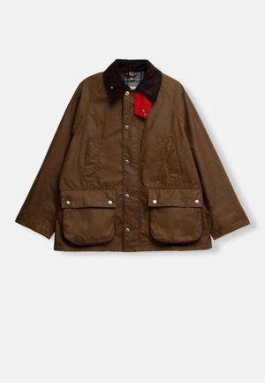 Veste marron avec un col en velours côtelé, accent rouge, boutons-pression, deux grandes poches avant et une coupe légèrement oversized. Tissu imperméable.
