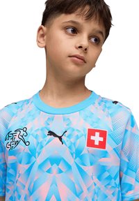 T-shirt de sport à motifs bleus et roses avec un col rond, arborant le logo Puma et un emblème du drapeau suisse, confectionné en tissu léger.