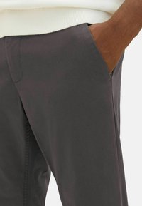 Dunkelgraue Baumwollmischungshose mit glatter Textur, schrägen Taschen und Nahtdetails am Bund. Bietet eine entspannte Passform.