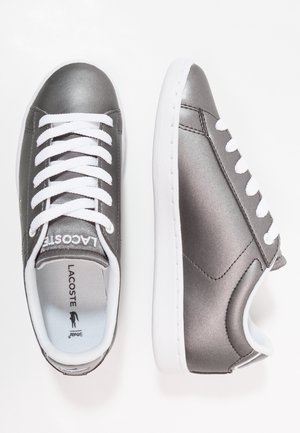 Sneakers sintetiche grigie con lacci bianchi e suole in gomma. Superficie liscia con una leggera lucentezza. Include il marchio sulla linguetta e nella soletta.