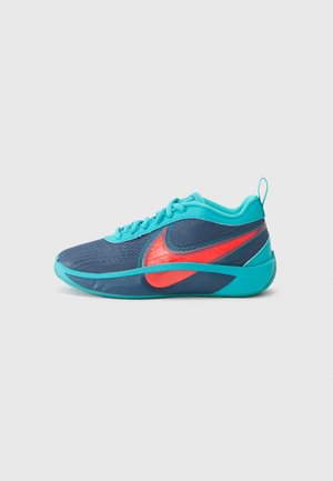 Zapatilla deportiva azul con parte superior de malla, acentos turquesas y un swoosh rojo de Nike. Presenta una superficie texturizada y un diseño de puntera redondeada.