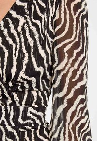 Abito a righe zebrate in bianco e nero con design a portafoglio, caratterizzato da un fronte in tessuto liscio e maniche trasparenti e testurizzate.