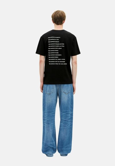Juodas medvilnės marškinėliai su baltais užrašais, ant nugaros esantis įvairių frazių derinys. Suderinti su laisvos formos šviesiai mėlynos džinsinės kelnės.