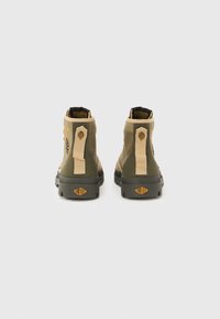 Ζευγάρι ψηλά μποτάκια Palladium σε πράσινο και μπεζ χρώμα, εμφανιζόμενα από πίσω με φόντο απλό λευκό.