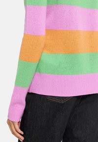 Pull rayé multicolore avec des rayures vertes, roses et orange ; tissu en tricot texturé ; poignets et ourlet côtelés.