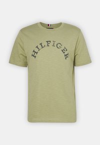 Lys grøn bomulds T-shirt med korte ærmer, rund halsudskæring og mørkegrå "HILFIGER" tekst i bue. Blød tekstur med et subtilt mønster.