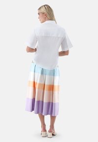 White short-sleeved blouse paired with a multi-colored pleated skirt featuring horizontal stripes in blue, orange, and lavender tones.