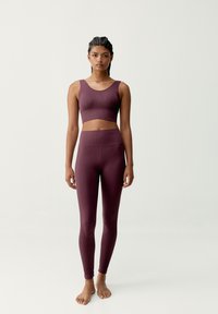 Conjunto de ropa deportiva en color malva que incluye un top corto sin mangas de canalé y leggings de cintura alta con una textura suave y un diseño ajustado.