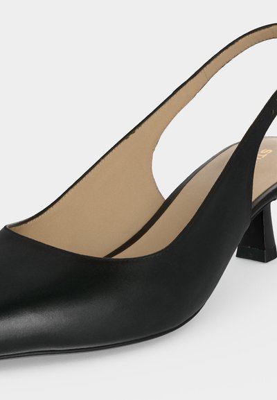 Chaussure slingback noire en cuir à bout pointu et petit talon carré, présentée en gros plan sur un fond clair et uni.