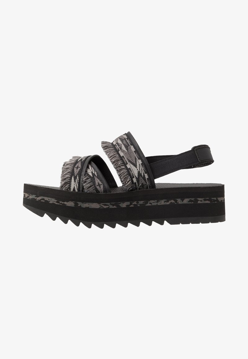 Sandales à plateforme noires avec deux larges brides en tissu texturé et à motif, ornées de détails en franges, montées sur une semelle crantée.