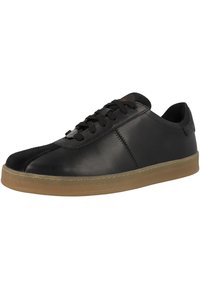 Zapatillas de cuero negro con una parte superior lisa y punta redonda. Cuenta con cordones negros, suela de goma y sutiles detalles de costura en los laterales.