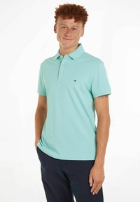Lyseblå polo skjorte i myk bomullsstoff, med krage, korte ermer og liten brodert logo på brystet.