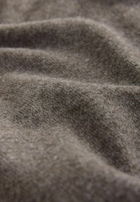 Mekana, teksturirana smeđa tkanina sa blago dlačastom površinom, s nježnim naborima i glatkim izgledom, idealna za odjeću ili presvlake.