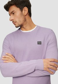 Hellvioletter strukturierter Pullover mit Rundhalsausschnitt und gerippten Bündchen, ausgestattet mit einem kleinen schwarzen Logo-Patch auf der Brust.