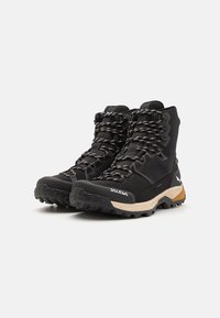Botas de senderismo negras con un upper sintético texturizado, sistema de lazado duradero, entresuela acolchada y suela exterior resistente para tracción.
