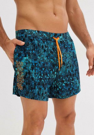 Badehorts in Blau und Schwarz mit geometrischem Muster. Verfügt über einen elastischen Bund mit orangefarbenem Kordelzug und seitlichen Taschen. "#WAVE"-Schriftzug.