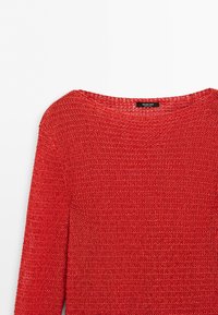 Red loosely knit long-sleeve sweater with round neckline and brand label inside the collar on a white background.
