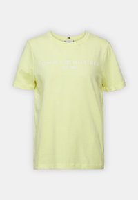 Camiseta amarilla clara de manga corta con cuello redondo y texto blanco "Tommy Hilfiger EST. 1985" en el pecho.