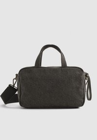 Zwarte stoffen tas met twee korte handvatten, een afneembare schouderband en ritsluiting. Rectangulaire vorm met een gestructureerd oppervlak en minimalistisch ontwerp.