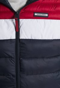 Padded jacket z poziomymi blokami kolorów w czerwonym, białym i granatowym. Zamek błyskawiczny z markowym logo. Gładkie, błyszczące wykończenie z tekstyliów.