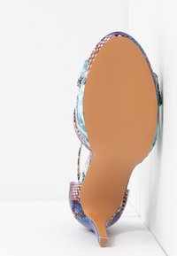 Chaussure à talon haut avec un dessus en cuir serpent texturé et multicolore, dotée d'un bout pointu et d'un talon fin. Semelle en caoutchouc beige.