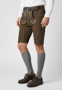 Bruine lederhosen shorts met decoratieve stiksels, gecombineerd met grijze kniehoge sokken en donkerbruine schoenen, met een decoratieve ceintuurgesp.