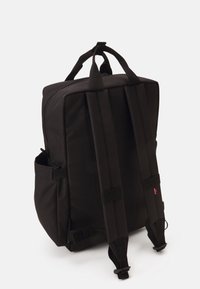 Sac à dos en tissu noir avec des bretelles rembourrées, une fermeture zippée, des poches latérales et une forme rectangulaire. Il est doté de coutures renforcées et d'un design épuré.