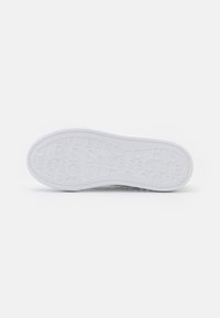 Biała podeszwa sneakerów z fakturowaną powierzchnią i wytłoczonym wzorem marki, z gładkim gumowym wykończeniem.