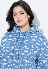 Blå hoodie av mjukt tyg med vit "STAR"-tryck, metallisk stjärndesign och dragsko med silverändar.