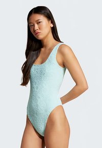 Fato de banho azul-claro com relevo floral, decote redondo e cintura alta. Feito de material elástico texturizado, adequado para nadar.