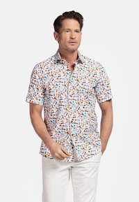 Chemise à manches courtes en tissu blanc, présentant un motif coloré de fruits et de motifs floraux. Texture lisse, design de col classique.