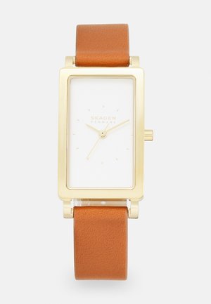Rechteckige Skagen-Uhr mit weißem Ziffernblatt, Gehäuse in Goldfarbe und braunem Lederarmband. Verfügt über einfache Stundenmarkierungen und eine kleine Krone.