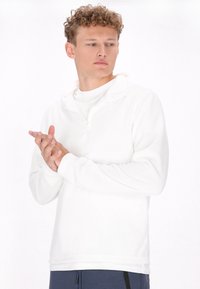 Hvid fleece pullover med kvart-zip krave, lange ærmer og en blød tekstur. Sat sammen med blå atletiske bukser, minimalistisk design.