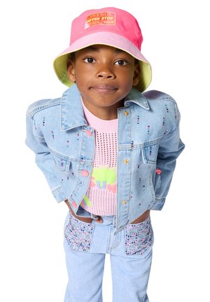 Bambino che indossa un cappello a secchiello rosa e verde, giacca di jeans chiaro e pantaloni con decorazioni di perline colorate, e una maglietta rosa lavorata a maglia.