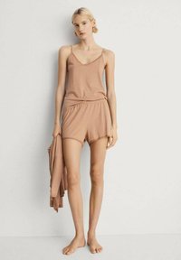 Lichtbruin loungewear set met een cami-top met kant en bijpassende shorts. Zachte stof; comfortabele pasvorm met een gladde textuur.