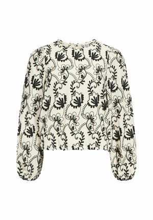 Haut crème à manches longues bouffantes avec une broderie florale noire complexe et un col rond. Tissu texturé avec une coupe décontractée.