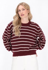 Burgundowy sweter w paski z białymi liniami, prążkowana struktura, okrągły dekolt, bufiaste rękawy oraz dekoracyjne guziki na ramieniu.