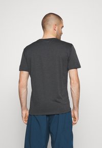 Graues Kurzarm-T-Shirt aus strukturiertem Stoff, mit Rundhalsausschnitt und lässiger Passform, getragen mit blauen Shorts.