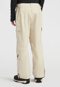 Beige snöbyxor med cargo-fickor, förstärkta anklar och en lös passform för rörlighet. Tillverkade av slitstarkt, väderbeständigt material.