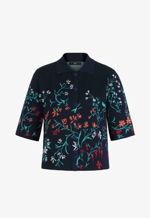 Tumesinise lühikeste varrukatega kardigan kraega, ees nööpidega ja mitmevärvilise lillemustriga rohelistes, punastes, oranžides ja valgetes toonides.